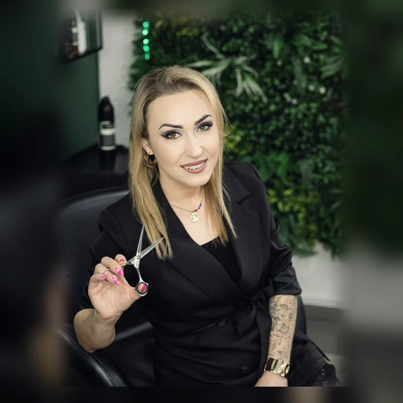 Jowita Litwin w swoim salonie fryzjerskim w Goleniowie na tle zielonej ściany roślin